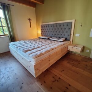 Zirbenbett Davos in Dachau - mit Lodenpolster in grau und Nachttisch schwebend